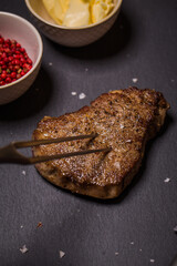Juicy medium Beef Rib Eye steak son wooden board with fork and knife herbs spices and salt.