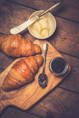 French croissant. Freshly baked croissants with jam on wooden background. Tasty croissants with copy space