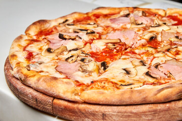 Fresh pizza with bacon, tomatoes, mushrooms and cheese on a light background. Close-up, selective focus