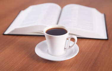 Book and coffee are isolated on a wooden background.