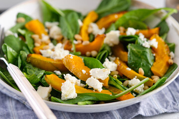 Salad of spinach leaves, baked pumpkin and feta cheese with nuts. Healthy food.