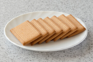 Rectangular shortbread cookies and chocolates in a white plate on a marble top.