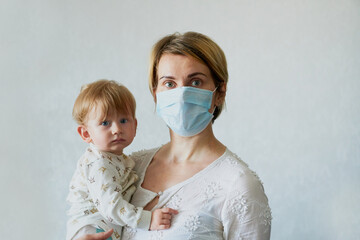 Young woman in a medical mask with a baby in her arms On white