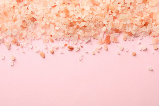 Pink himalayan salt on pink background, space for text