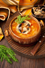 Vegetables soup with cabbage and mushrooms in bowl on wooden table