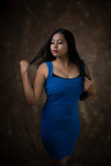 Fototapeta premium Studio portrait of an young Indian girl in blue western dress in front of textured background. Fashion portrait photography