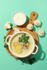 Concept of tasty lunch with bowl of mushroom soup on mint background