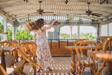 Fototapeta na wymiar girl dancing in cafe on the beach. young slim beautiful woman on sunset beach, playful, dancing, running, bohemian outfit, indie style, summer vacation, sunny, having fun, positive mood, romantic