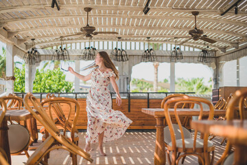 girl dancing in cafe on the beach. young slim beautiful woman on sunset beach, playful, dancing, running, bohemian outfit, indie style, summer vacation, sunny, having fun, positive mood, romantic