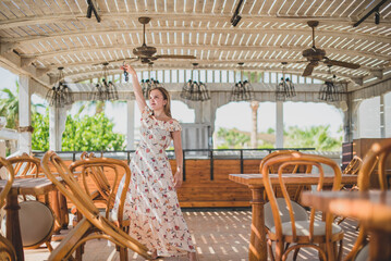 girl dancing in cafe on the beach. young slim beautiful woman on sunset beach, playful, dancing, running, bohemian outfit, indie style, summer vacation, sunny, having fun, positive mood, romantic