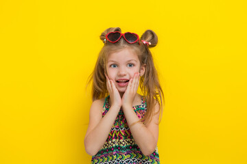Cute little girl in sun glasses on the yellow background in the studio.