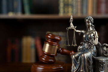 Law and justice concept. Judge chamber. Themis sculpture and judge’s gavel on brown desk....