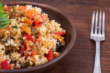 Couscous with stewed vegetables is a Moroccan, Algerian and Tunisian dish. Couscous mixed with stewed vegetables in a traditional clay plate