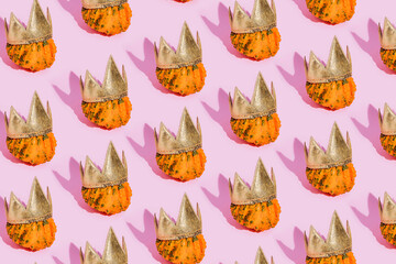 Fall pattern made of pumpkins with golden crown on a pink background. Autumn, Halloween or...
