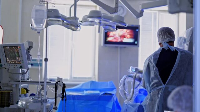 Minimally invasive operation. Modern surgical room. Doctor looks on the medical monitor with surgical process. Innovative technologies in medicine.