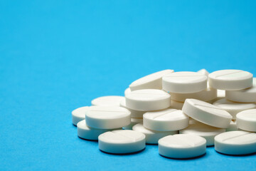 group of white pills or tablets on blue background