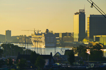 Modern cruiseship or cruise ship liner arrival into port of Amsterdam, Holland with city skyline...