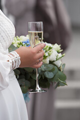 Bride with a wedding bouquet of flowers and holding a glass of champagne. Wedding ring. Wedding ceremony.