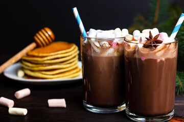 Christmas snack with hot chocolate and marshmallows on the background of a pancake with honey or wedge syrup