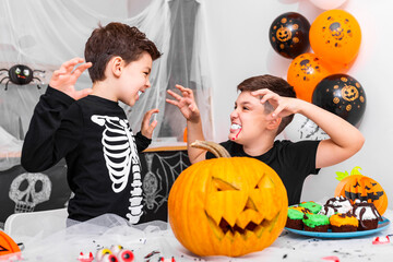 Happy Halloween! Attractive young boy with his big brother are preparing for Halloween party. Brothers in costumes are having fun and scaring each other