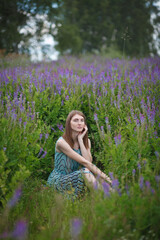 beautiful red-haired girl walking in a field of purple flowers