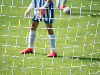 Young football goalkeeper in playground. Out of focus