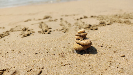 Fototapeta na wymiar zen stones laid out by hand lying on sand of sea beach