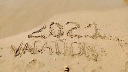 Text Vacation written in the sand of sea beach