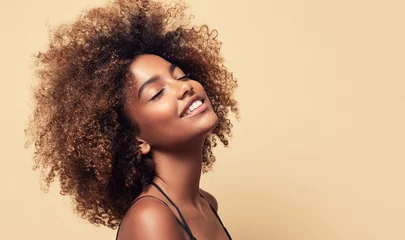 Fotobehang Kapsalon Beauty portrait of african american girl with clean healthy skin on beige background. Smiling dreamy beautiful black woman.Curly  hair in afro style   © Sofia Zhuravetc
