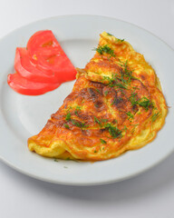 Scrambled eggs with fresh herbs and tomates on a white background. Delicious breakfast concept.