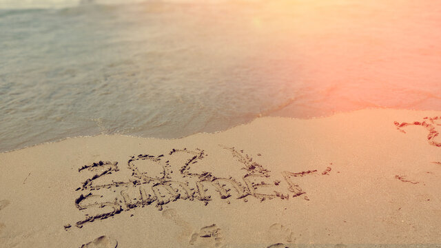 New Year 2021 and wave erasing 2020 year written in the sand