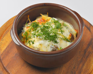 Baked potatoes with mushrooms and cheese in a pot. Delicious dinner. Isolated on white background.