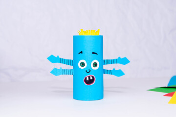 Halloween decoration. DIY and kids creativity concept. One blue monster made from toilet rolls on a white background.