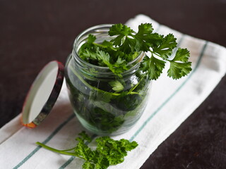 Glass jar with fresh parsley. The process of preserving fresh herbs for a long time. We put in a glass jar, under the lid and in the refrigerator.