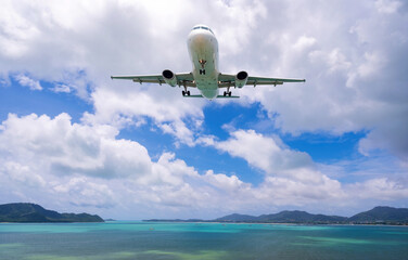 Fototapeta na wymiar Commercial airplane landing above sea and clear blue sky over beautiful scenery nature background.