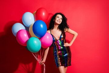 Photo of cute young girl hold many balloons look up empty space wear glossy short dress isolated...
