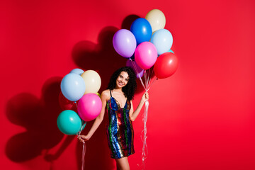Photo of charming girl hold many balloons shiny beaming smile wear glossy short dress isolated vibrant red color background
