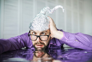 Bearded funny man in a cap of aluminum foil. Concept art phobias.Conspiracy theory. Conspiracy....