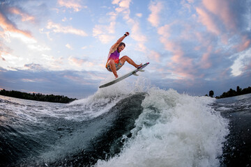 athletic man riding large wave doing jumps and tricks on the surf style wakeboard