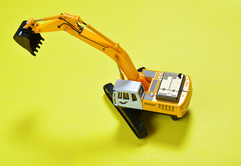 toy yellow excavator with a black bucket on a yellow background. the concept of construction and...