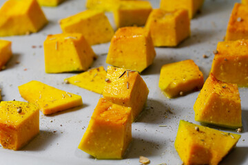 Baked pumpkin. Diced pumpkin on a baking sheet. Pumpkin cooked in the oven. Macro photography of food. A traditional autumn dish of baked pumpkin. Close-up.