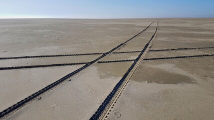 Spuren vom Auto im Sand die sich kreuzen vor blauem Himmel und Horizont ohne Menschen