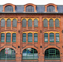 red brick facade of old industrial building with large glass windows