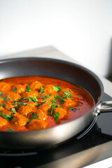 Meatballs in tomato sauce with green onion topping and parsley in the black pan