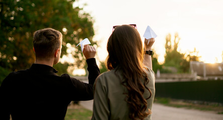 Obraz premium young family having fun outdoors, throw paper plane, feel happy, smile and laugh