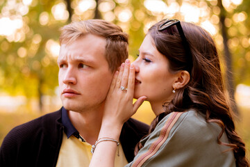 Naklejka premium couple of young man and woman tell secret each other, whisper to the ear