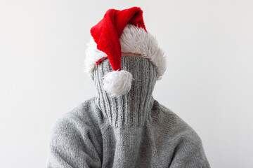 A teenage girl in a Santa hat pulled the collar of her sweater over her face. New year's concept in...