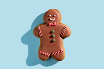Christmas gingerbread man. Festive bakery food. Homemade cookies. Smiling biscuit figure boy with chocolate icing colorful decor isolated on blue pastel.