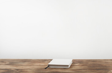 Closed book notepad on a wooden table.