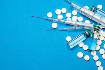 Top view of Pills, Syringe And Ampoule With Vaccination On blue background with copy space